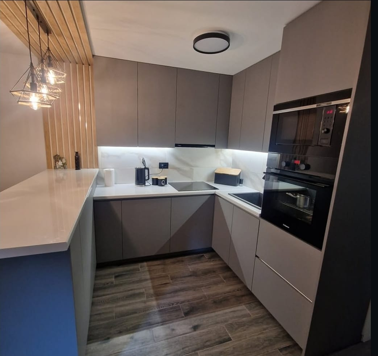 Moderna kuhinja, sa svim potrebnim elementima u mesavini sive i drvenaste boje.